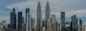 Kuala Lumpur skyline with the Petronas Twin Towers among glass skyscrapers under a blue sky,