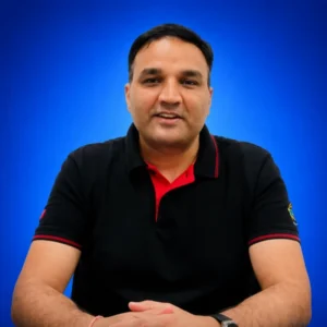 Front-facing man in a black polo with red accents, seated with hands folded, blue gradient background.