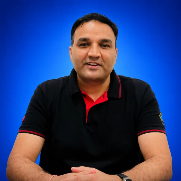 Front-facing man in a black polo with red accents, seated with hands folded, blue gradient background.