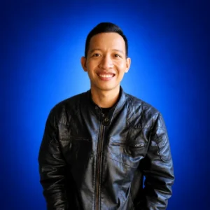 Portrait of a smiling man in a black leather jacket against a blue gradient background.