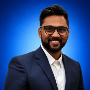 Smiling man in a navy suit and white shirt, head-and-shoulders portrait against a blue gradient background.