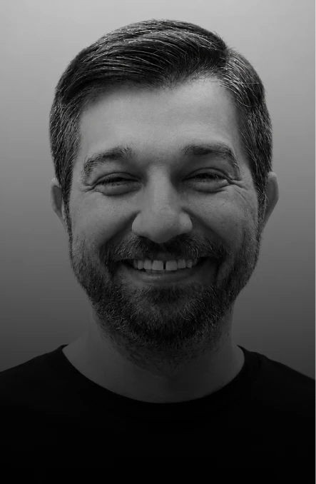 Grayscale head-and-shoulders portrait of a smiling man with short dark hair and a beard.