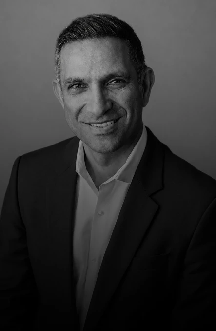 Smiling professional man in a dark suit and white shirt, head-and-shoulders portrait, grayscale.