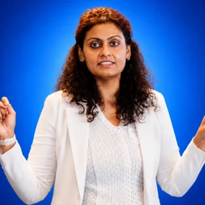 Professional woman in a white blazer gesturing with her hands while speaking against a blue background