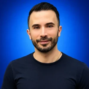Arash Taheri Portrait of a smiling man with short dark hair and stubble, wearing a navy shirt against a blue gradient background.