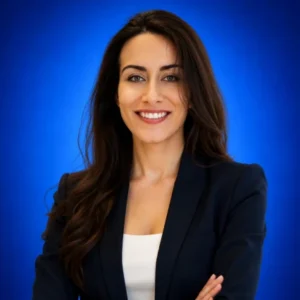Bahar Rostamkhani Professional headshot: smiling woman in a navy blazer against a blue background, arms crossed.