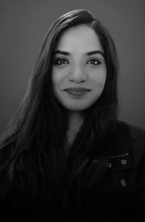 Portrait of a woman with long dark hair, smiling at the camera, in grayscale.