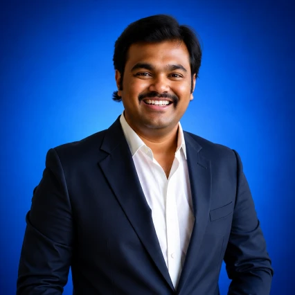 Smiling man in a navy suit and white shirt posing against a blue backdrop.