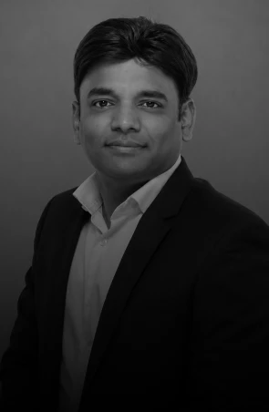 Professional head-and-shoulders portrait of a man in a dark suit and white shirt, neutral background.