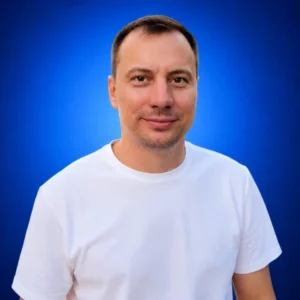 Taras Buriak Portrait of a man in a white T-shirt smiling against a blue gradient background.