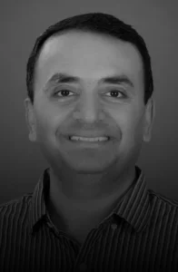 Grayscale head-and-shoulders portrait of a smiling man wearing a striped shirt facing the camera