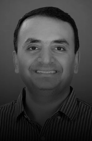 Grayscale head-and-shoulders portrait of a smiling man wearing a striped shirt facing the camera